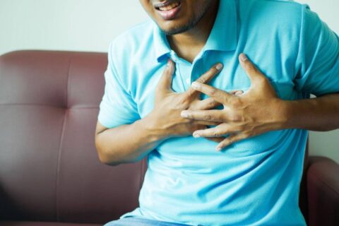 person holding chest in pain showing the physical reality of how to deal with heartbreak