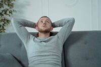 person exhausted on couch showing what really happens before learning how to stop being lazy