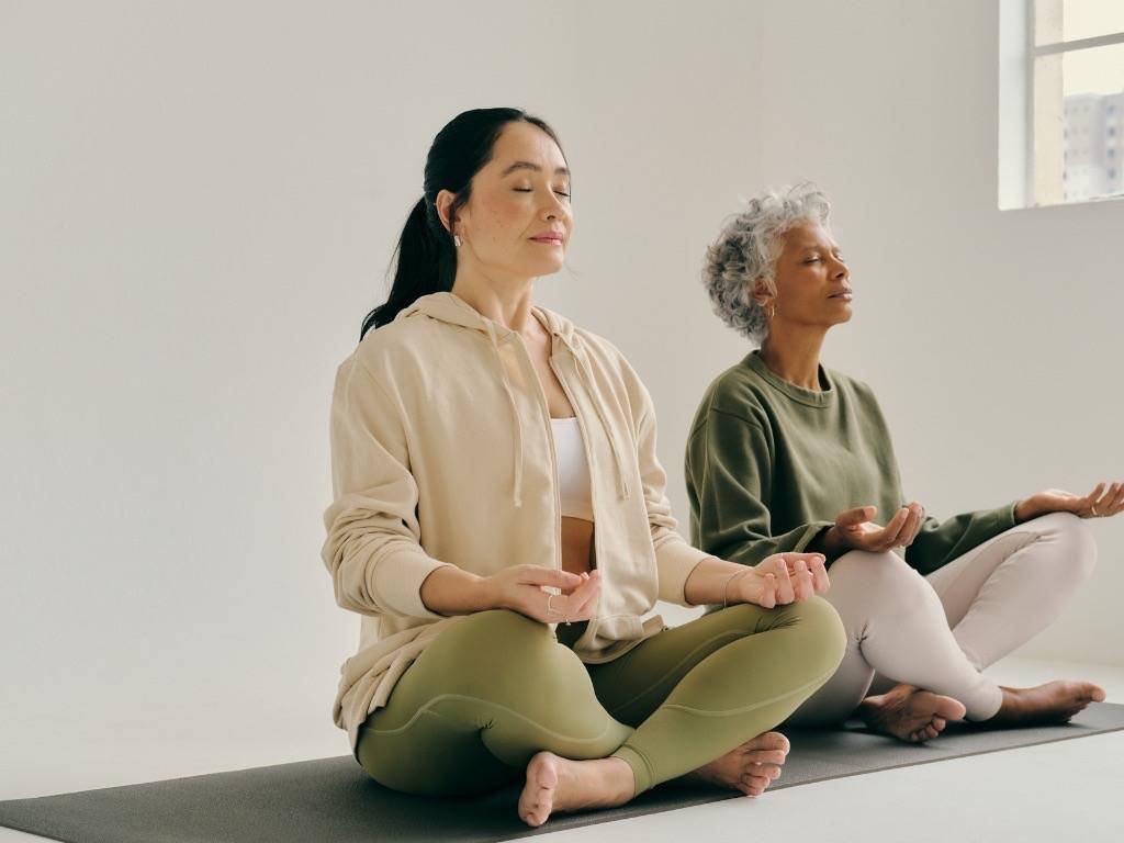 Cultivate mindfulness – two women practicing mindfulness meditation indoors