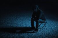 person sitting alone at night carrying emotional weight while learning how to forgive yourself