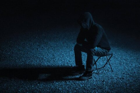person sitting alone at night carrying emotional weight while learning how to forgive yourself