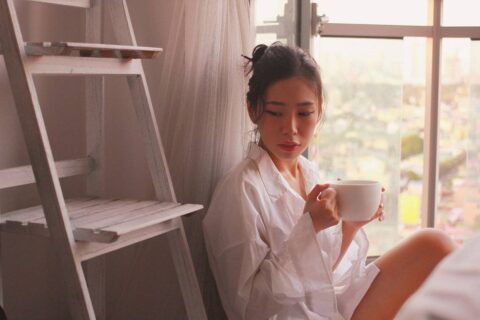 person sitting by window with coffee practicing gratitude in a quiet morning moment