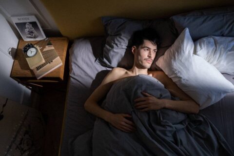 person lying awake in bed at night struggling with how to stop overthinking at night