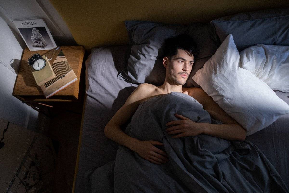person lying awake in bed at night struggling with how to stop overthinking at night