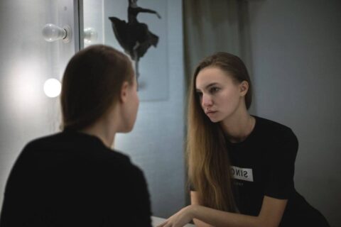 person looking in mirror honestly reflecting on how to be more confident