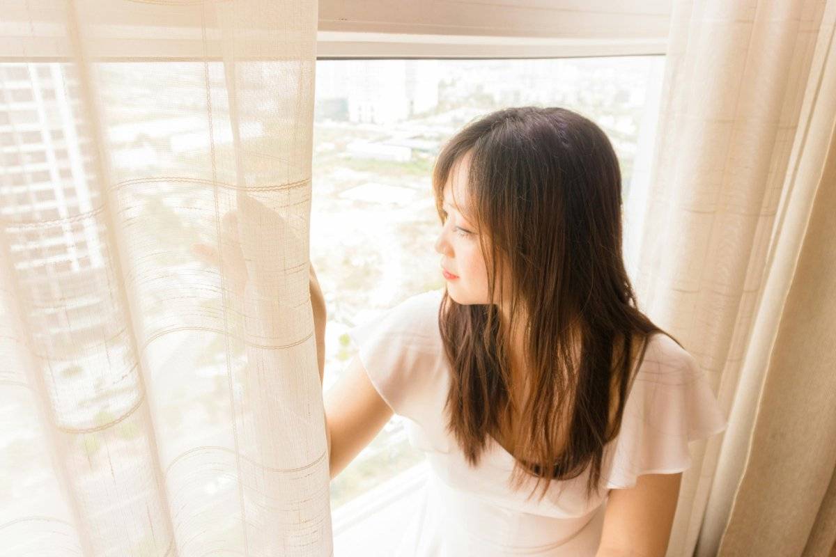 person sitting alone by window at night struggling with how to stop thinking of someone