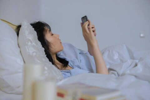 person lying in bed with phone instead of following morning routine ideas