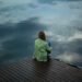 Woman sitting alone by the water feeling depressed and isolated