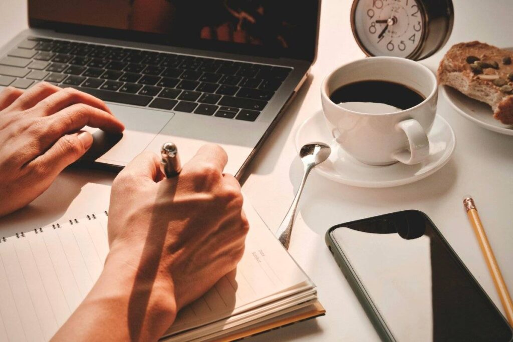 person writing morning intention in notebook as part of productive morning routine ideas