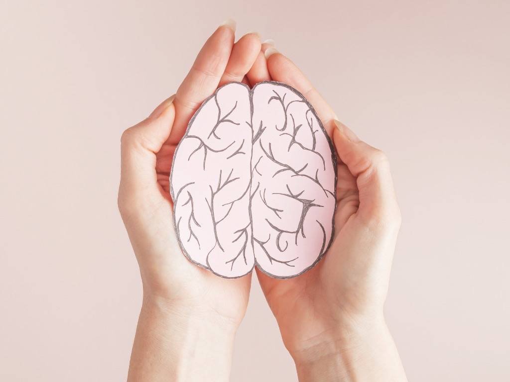 Hands holding a brain illustration symbolizing mental health awareness and support for breaking stigma.