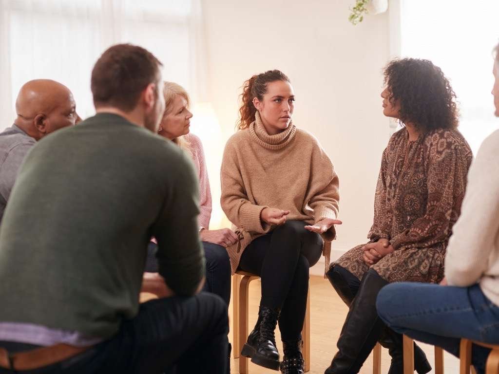 Diverse support group discussing mental health awareness and treatment beyond severe cases.