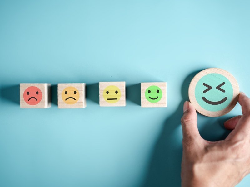 Maintaining mental health concept with emotion faces scale from sad to happy, highlighting social connection and anxiety relief.