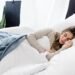 Woman sleeping peacefully with blanket, highlighting the link between sleep and mental health