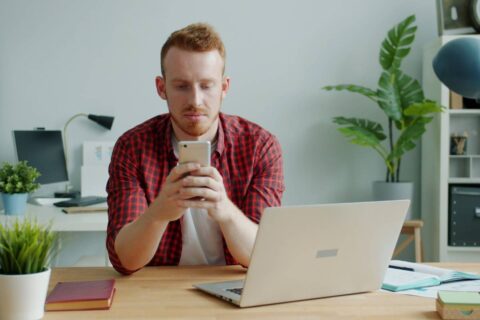 person distracted at desk with phone showing the honest struggle of learning how to focus better