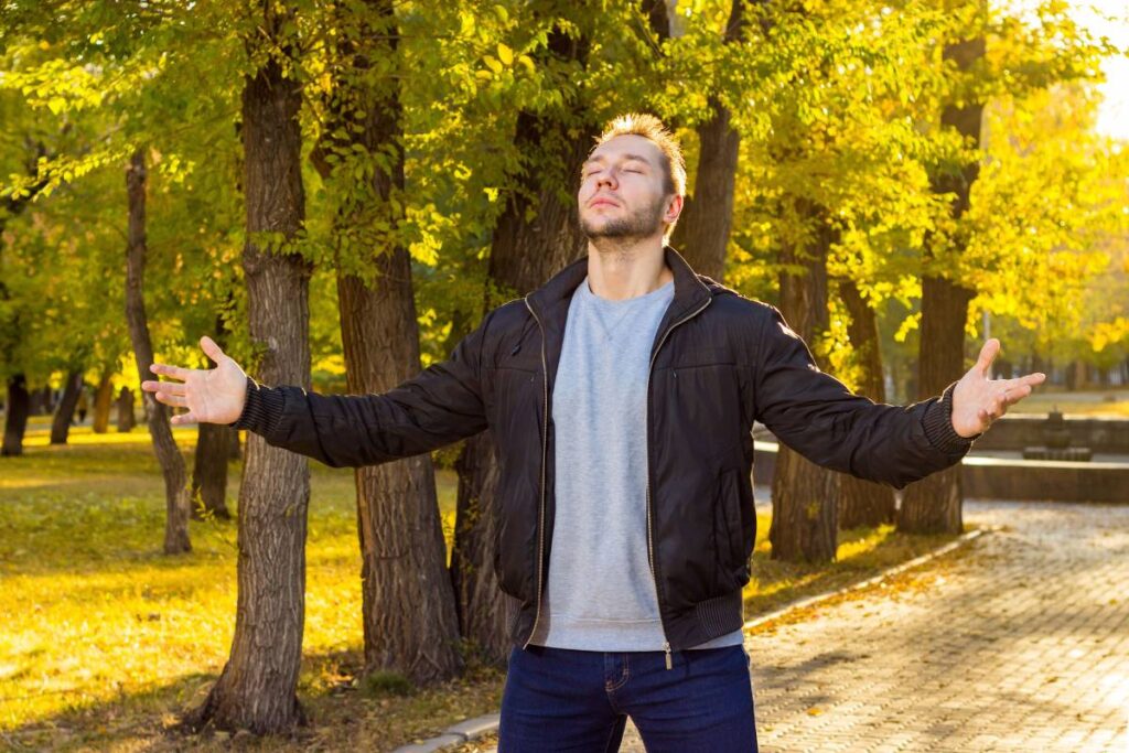 person taking deep breath outdoors showing a key practice in how to deal with stress