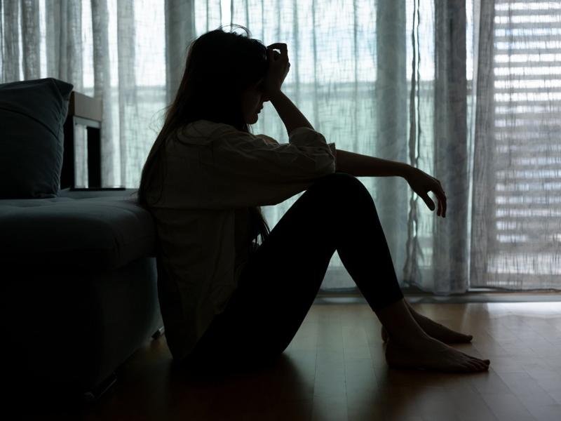Woman sitting alone in a dark room, showing signs of silent depression and emotional struggle