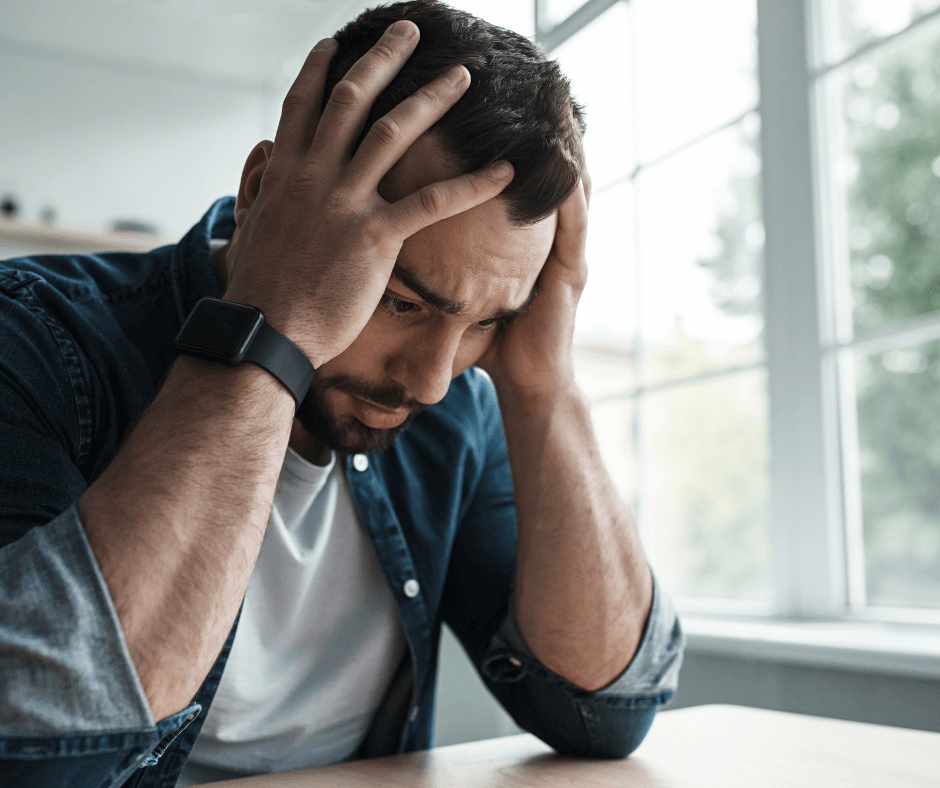 Stressed man holding head in hands due to anxiety- how to deal with anxiety in real life