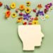 Human head silhouette with colorful flowers symbolizing mental health and positive thinking