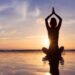 Woman practicing mindfulness meditation at sunrise on the beach for better mental health and well-being