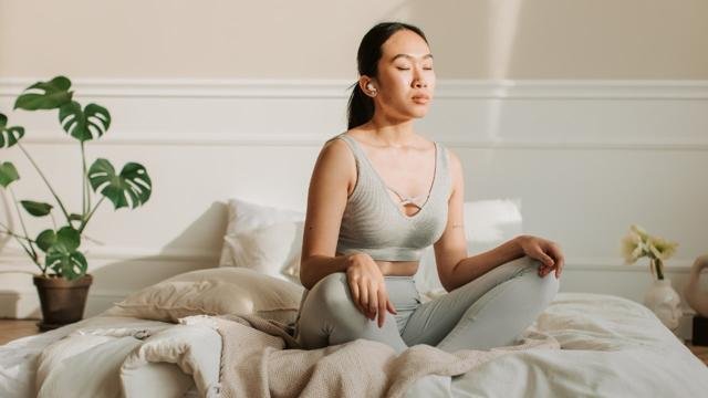 Woman practicing mindfulness meditation on bed for better mental wellness