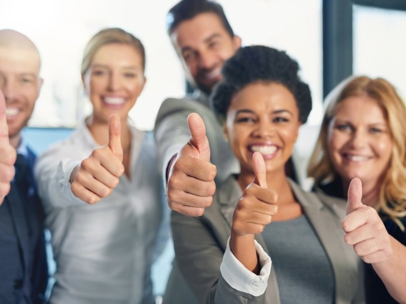 Group of smiling people showing thumbs up – example of toxic positivity in modern workplaces