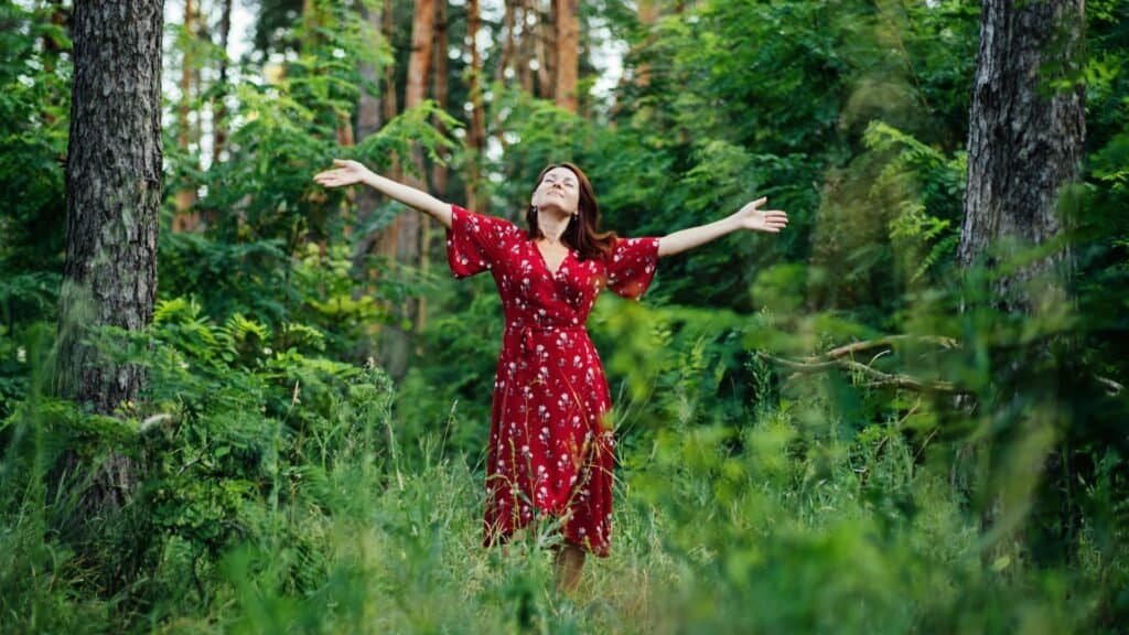 Woman in red dress enjoying nature in the forest, symbolizing stress relief and natural ways to reduce anxiety.