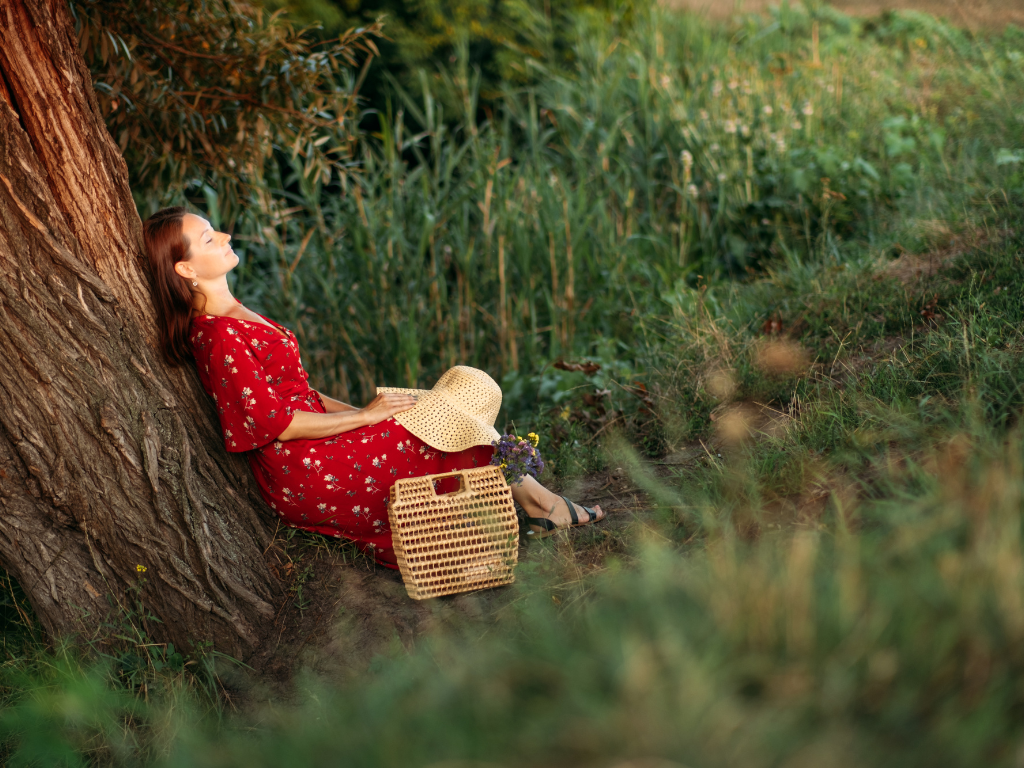Woman relaxing under a tree in nature, practicing calm moments to reduce anxiety naturally and boost mental wellness.