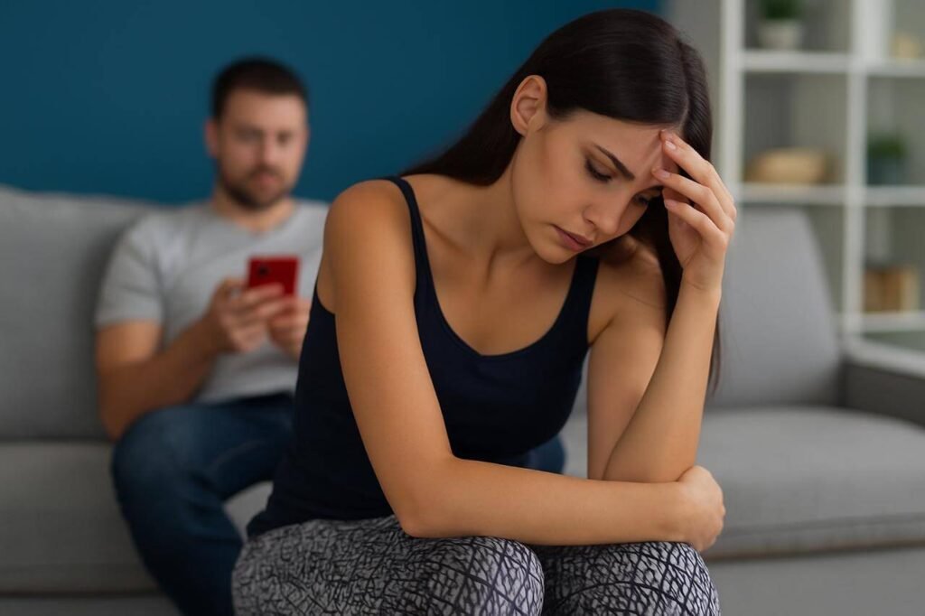 A couple sitting apart on a bed, showing emotional tension and resentment in their relationship.Let Go of Resentment in Relationships