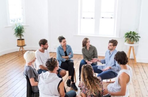 Group of people sitting in a circle during a support session, discussing mental health and wellness
