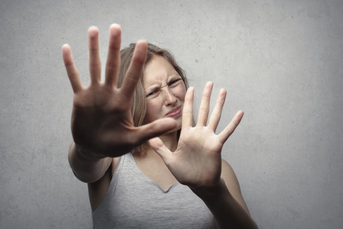 Fearful woman covering her face with hands, symbolizing anxiety and trying to stop overthinking.