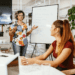 Confident woman giving a presentation to colleagues, showing how to develop charisma through body language and communication skills in a modern office setting.