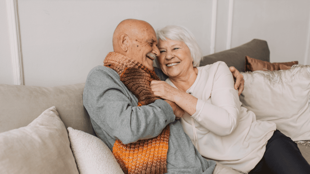 Happy senior couple showing physical intimacy on a cozy sofa, symbolizing emotional closeness and long-term love.