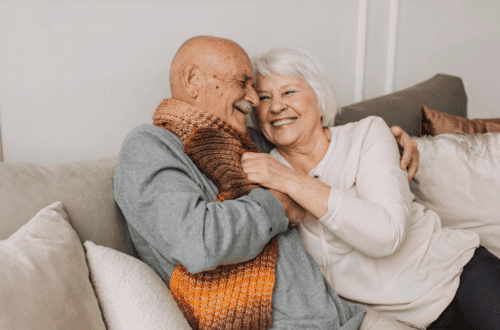 Happy senior couple showing physical intimacy on a cozy sofa, symbolizing emotional closeness and long-term love.