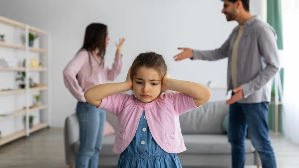 Child covering ears during parents’ argument — symbolizing trauma bonding and emotional pain.