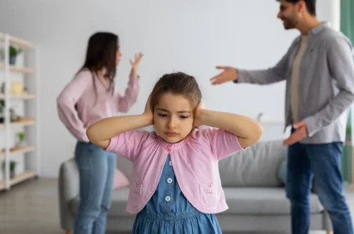 Child covering ears during parents’ argument — symbolizing trauma bonding and emotional pain.