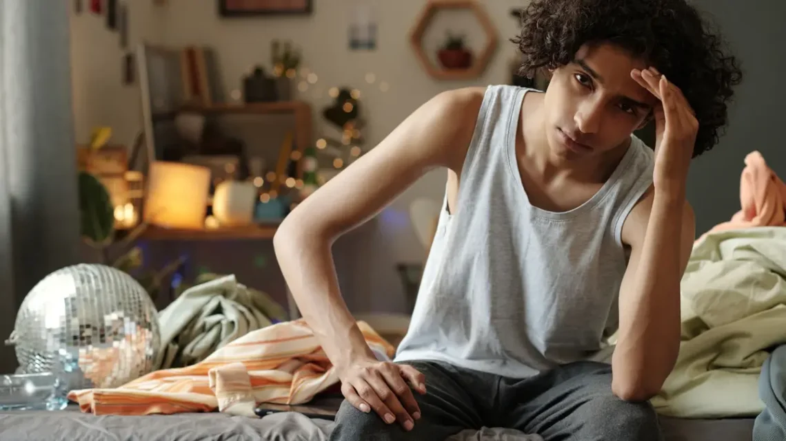 Alt Text: depression symptoms young person sitting alone feeling sad emotional distress