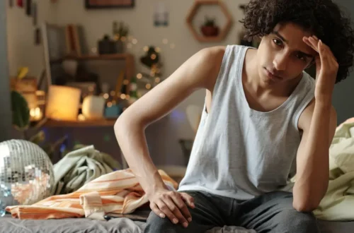 Alt Text: depression symptoms young person sitting alone feeling sad emotional distress