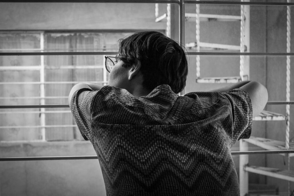 person alone by window showing the isolation that is one of the key signs of an unhealthy relationship