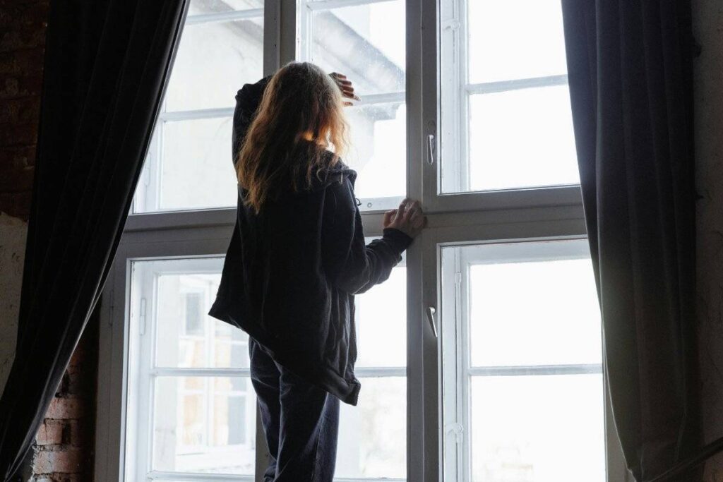person alone by window feeling isolated in an unhealthy relationship