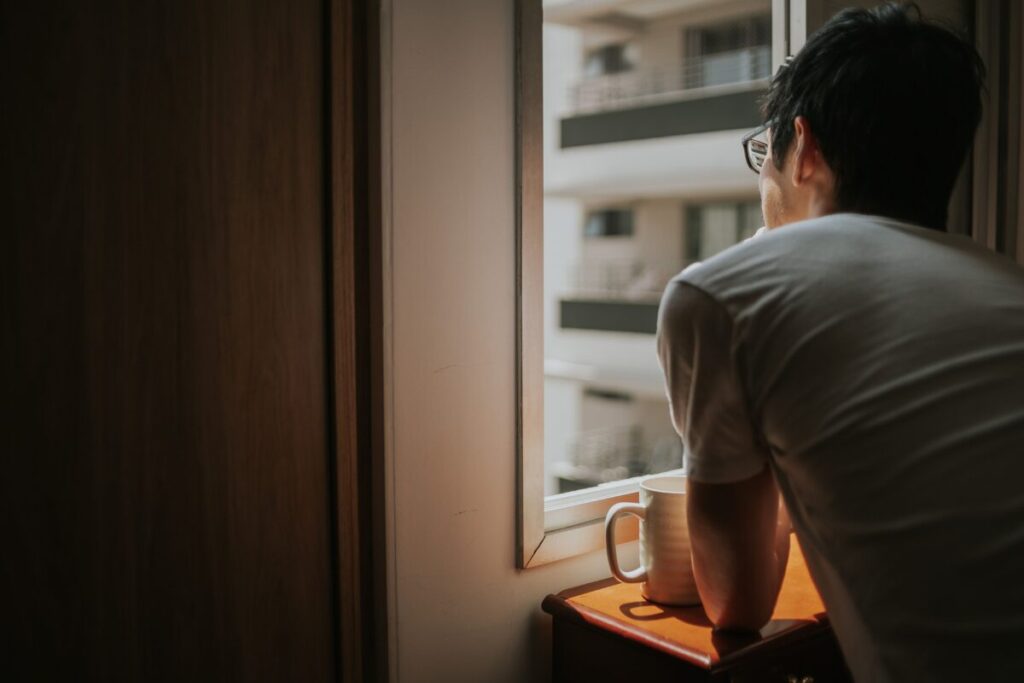 woman standing alone by a window, learning how to stop being a people pleaser